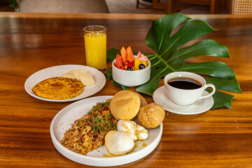 Colombian breakfast with arepas, coffee, bread, eggs, warmed rice and fruit