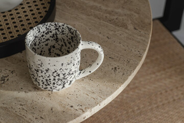 Black and white ceramic cup on travertine coffee table. Wabi-sabi interior details for decoration