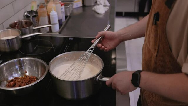 Stirring the sauce with a whisk, Carbonara sauce cooking for spaghetti and pasta. Cooking creamy pasta carbonara sauce. Boiling creamy white sauce. Italian Food. Slow motion video
