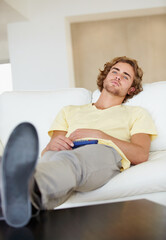 Fototapeta premium Bored man, remote control and watching tv on sofa with bad mood, chilling on streaming service in his home. Depression, lonely and sad male person in a living room with television, cable or movies
