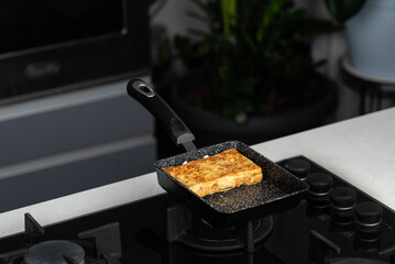 Chef man hands cooking Tamagoyaki or Tamago traditional Japanese Rolled Omelette recipe, made by...