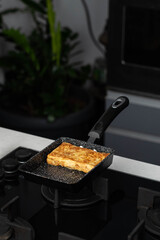 Chef man hands cooking Tamagoyaki or Tamago traditional Japanese Rolled Omelette recipe, made by rolling several layers of cooked scrambled egg in pan into a rectangular omelet.