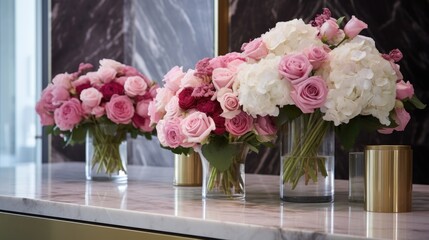  a row of vases filled with pink and white flowers sitting on top of a counter next to a mirror on which a vase is filled with pink and white flowers.