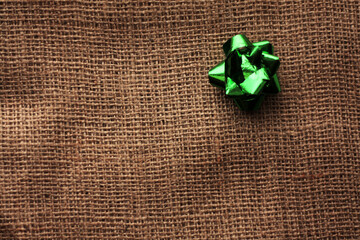 green shiny bow on burlap background