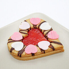 Heart-shaped cookie with strawberry jam isolated on white background. Traditional Linzer cookies on the plate close-up.