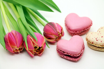 Bouquet of fresh pink tulips with heart-shaped macroons close-up.