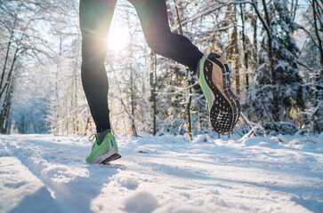 Running shoes sole close up image of winter jogger feet in running sneakers on the snowy park path...
