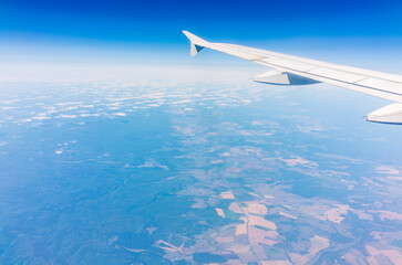 Aerial view from airplane window above green ground. View from the airplane window with beautiful clouds at sunrise