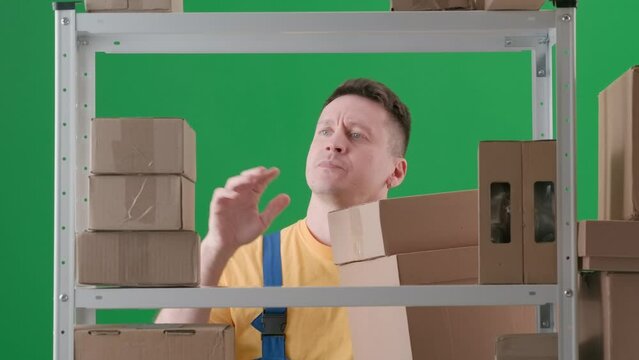 In the frame on a green background. Depicts a man in a working uniform. Demonstrates a storekeeper in a warehouse. He collects boxes, then they fall he freaks out and throws out all the others