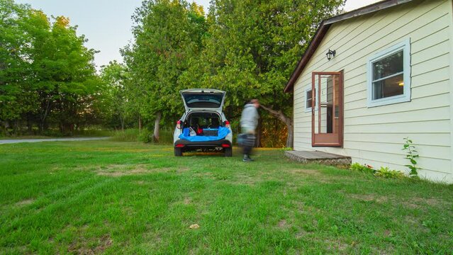 Timelapse of traveler unloads the car trunk with camping luggage and equipment near cabin or cottage in the wilderness of northern Ontario, Canada. Camping and exploring in summer season.