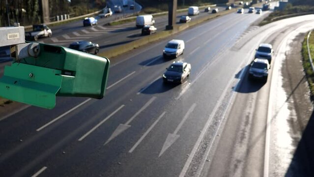 Close-up of green camera watching blurred motorway traffic down below, selective focus.