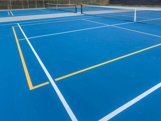 Close up photo of a outdoor blue tennis court with white lines combined with yellow, gold, pickleball lines.	 - obrazy, fototapety, plakaty