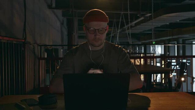 The Internet scammer puts on headphones and prepares to call the client to commit fraud. Hacker developer includes music for more enjoyable work. High quality 4k footage