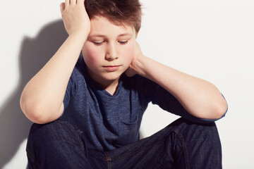 Sad, teenager and boy thinking in studio or sitting in white background with anxiety from fail in school. Mental health, stress and kid with worry from mistake or depressed emotions and ideas - obrazy, fototapety, plakaty
