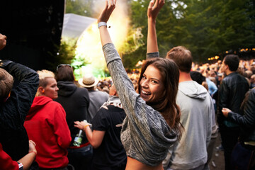 Happy woman, portrait and crowd in music festival for party, event or DJ concert in nature. Excited female person smile with hands up and audience at carnival, performance or summer fest outside