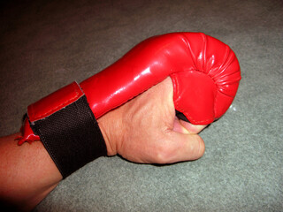 Big strong muscular male hand in a red kickboxing glove close up, sport equipment