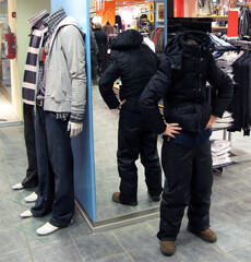 Man portrays a mannequin in a store. Man and mannequin side by side, funny situations