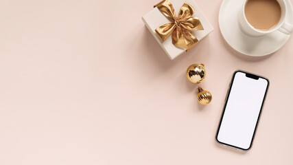smartphone with blank white screen, cup of coffee, gift box and Christmas balls on a pink...