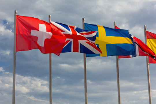 National flags of Switzerland, United Kingdom, Sweden, Norway and Spain against a cloudy sky