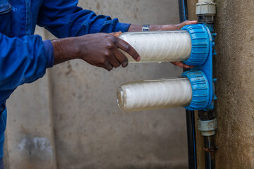 African plumber replaces the water filters. Clean water concept - obrazy, fototapety, plakaty