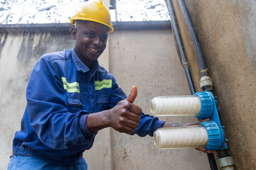 Thumbs up of a smiling African plumber, proud to have changed the water filters - obrazy, fototapety, plakaty