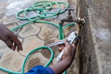 Close-up of the hands of an African plumber fixing the outside tap