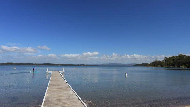Timber jetty and kayaks on Lake Macquarie of Australia in time lapse panorama.
