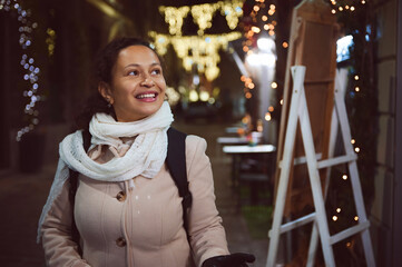 Authentic woman smiles while strolling the bright elegant street in the night time, decorated with lowing lanterns