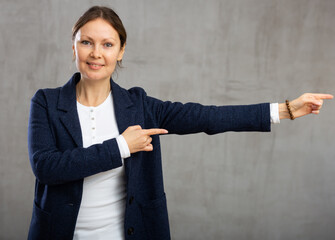 Smiling adult woman dressed in jacket gesturing in studio