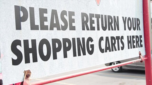 please return your shopping carts here metal sign outside outdoors in parking lot in summer