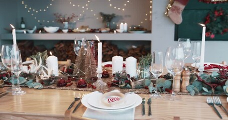 Table, christmas decoration and dinner with candle in living room, supper and celebration with rustic aesthetic. Plate, setting and napkin by candlelight at xmas party, mini trees and event in house