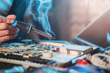 Close-up of a hand repairman specialist man repairs, and repairing electronics in a hardware repair shop - 693225926