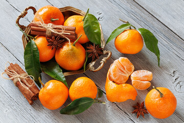 Mandarins fruits with leaves in a dish and on a wooden table, cinnamon and anise, sleigh decor. Christmas card.