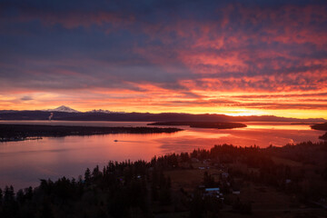 Fototapeta na wymiar Ferryboat crossing Hale Pass from Lummi Island to Gooseberry Point during a spectacular sunrise. Bellingham Bay and Mt. Baker can be seen in the background. Dramatic clouds make this image special.