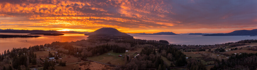 Panoramic Drone View of the South End of Lummi Island During a Spectacular Sunrise. Aerial shot of the sun rising over Bellingham Bay in the northwest corner of Washington state in the Salish Sea. - 693230592