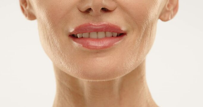 Close up of a 50 year old woman's face with snow white teeth and well cared for skin. She is smiling slightly. Skin care. Health and beauty. High quality 4k footage.