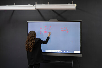 a math teacher in the school writing new exam task on the digital electronic blackboard