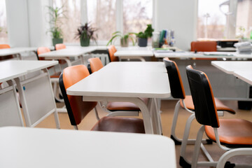 back to school concept, empty classroom with white tables and chairs