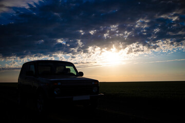 A car at sunset or dawn in a field.