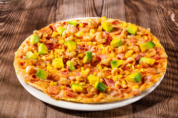 Pizza served with sausage, bacon, chicharron, sweet corn and pieces of avocado on a base of Neapolitan sauce and cheese
