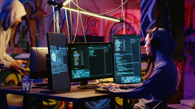 Hackers in secret bunker with graffiti walls writing code that spoofs their location, tricking cops. Rogue programmers running script pinging wrong location to cybercriminal law enforcement
