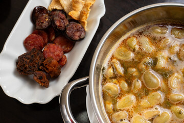 Traditional Portuguese dish of favas with chouriço, served in a rustic restaurant setting.