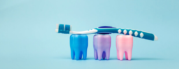 Toothbrush and mockups of three colorful teeth on a blue background. Teeth on a blue background. Dental health concept. Stomatology. Place for text. Oral health and dental inspection teeth. Dentistry.