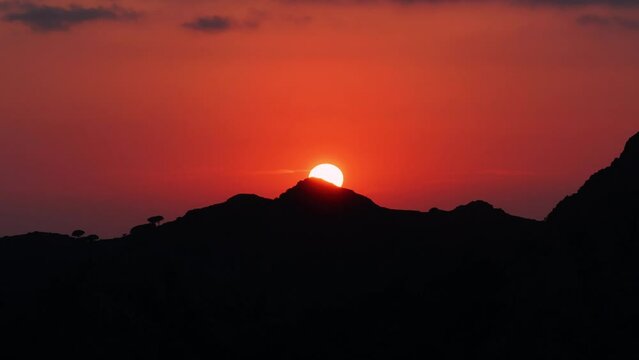 Il sole tramonta davanti a uno skyline nero in un cielo rosso fuoco