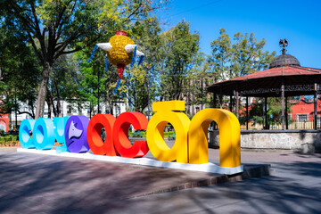Colorful giant letters with Coyoacan words in front kiosk Hidalgo Park garden in Mexico City...
