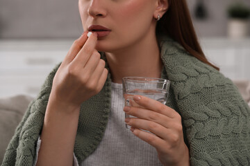 Woman with glass of water taking antidepressant pill on blurred background, closeup - obrazy, fototapety, plakaty
