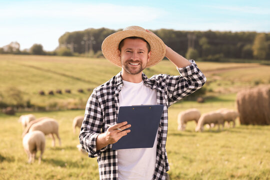 Smiling farmer with clipboard and animals on pasture