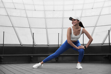 Beautiful woman in stylish sportswear stretching outdoors, space for text