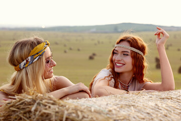 Beautiful hippie women near hay bale in field