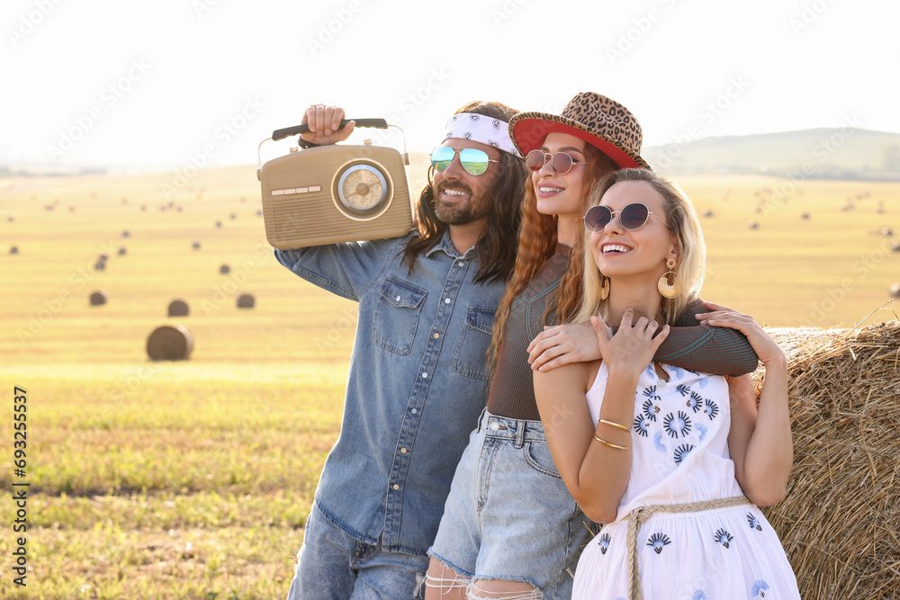 Sticker Happy hippie friends with radio receiver near hay bale in field, space for text